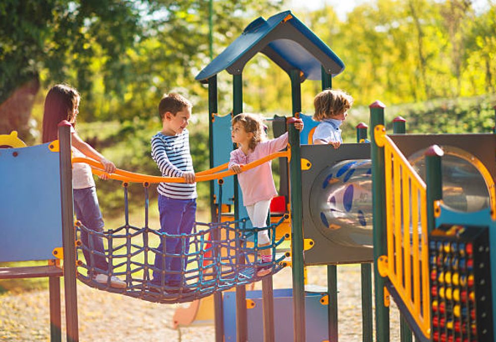 Small group of children having good time at jungle gym and talking.